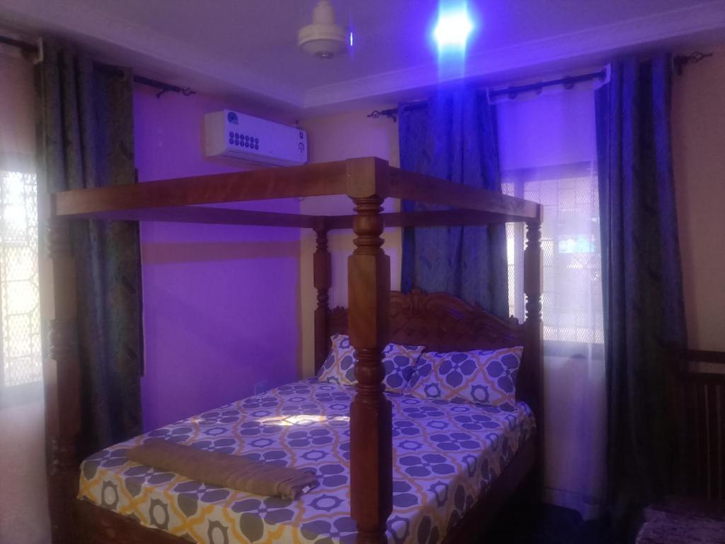 蒙巴萨Coasterian Apartment的紫色客房内的一间卧室配有一张天蓬床