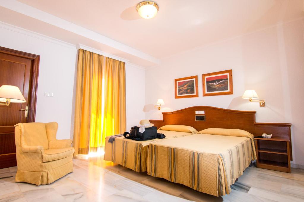 洛哈Hotel Abades Loja的配有一张床和一把椅子的酒店客房