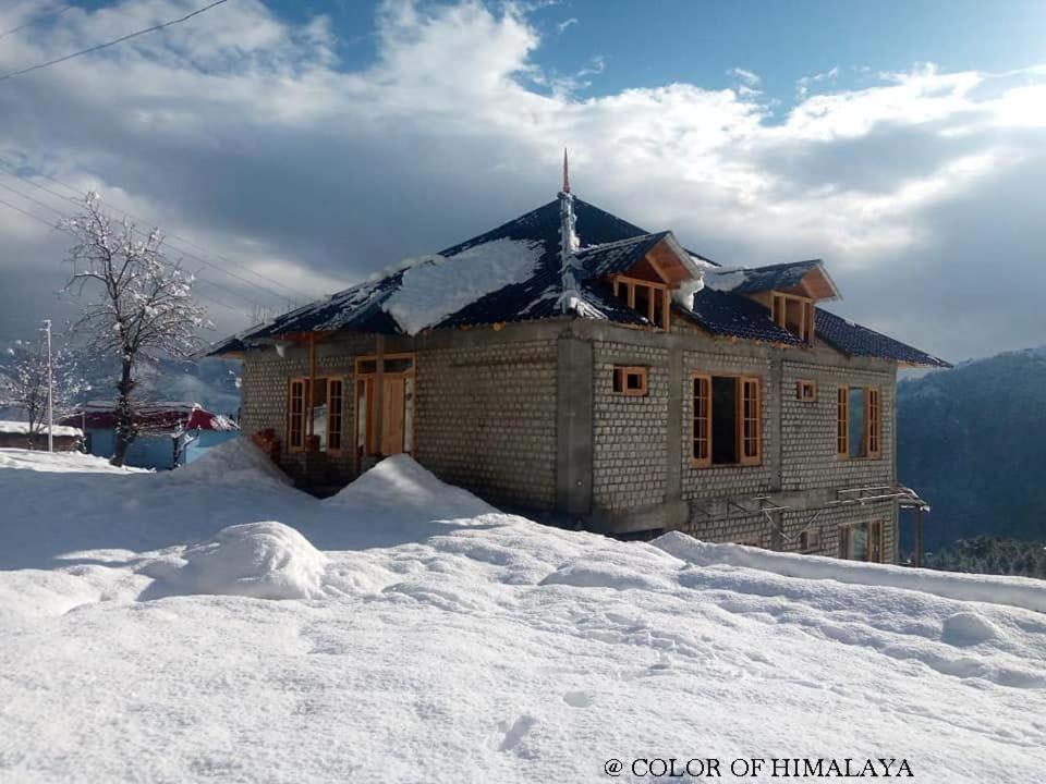 Khajjiar Loghouse at khajjiar lake的雪覆盖的山顶上的房子