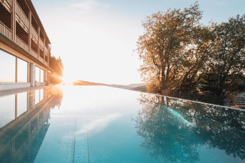HeilbrunnNaturhotel Bauernhofer的一座游泳池位于一座日光照耀的建筑前