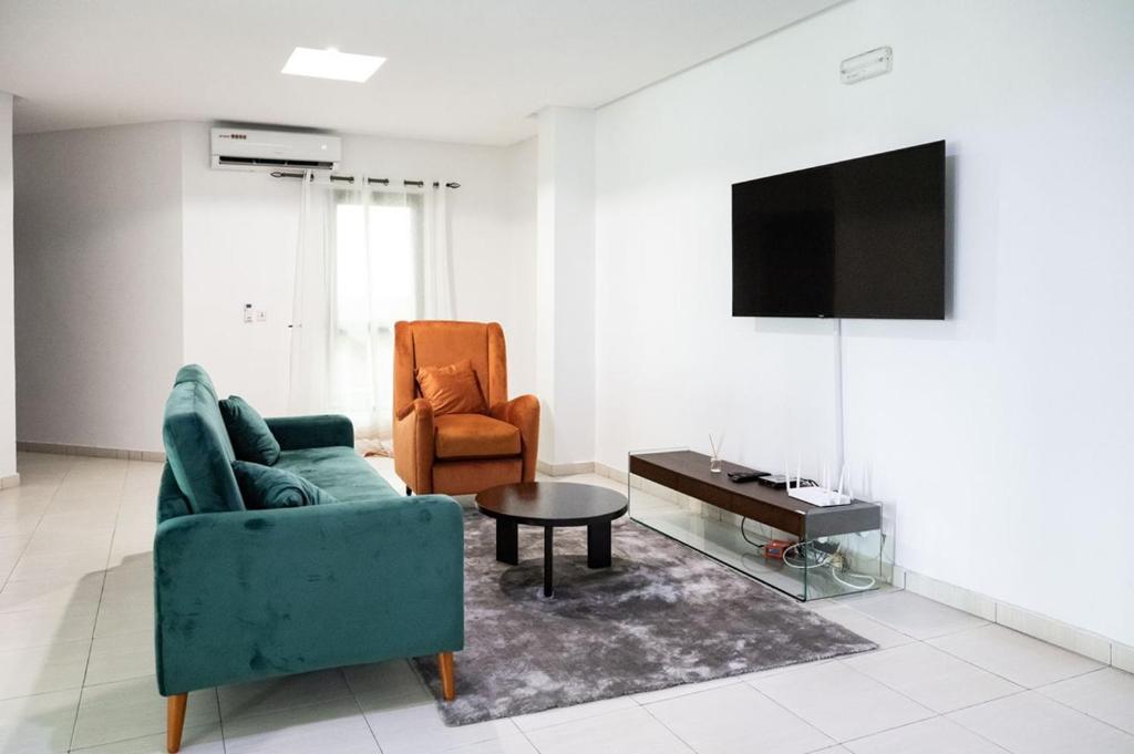 阿比让Sublime appartement à Cocody Riviera Bonoumin .的客厅配有沙发、椅子和电视