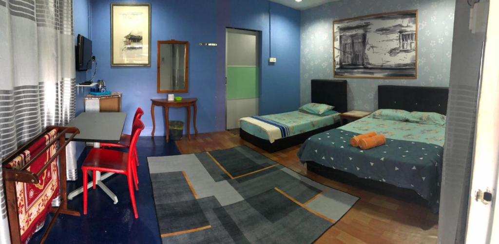 珍南海滩WAN'S ROOMSTAY LANGKAWI的客房设有两张床和一张带椅子的桌子。