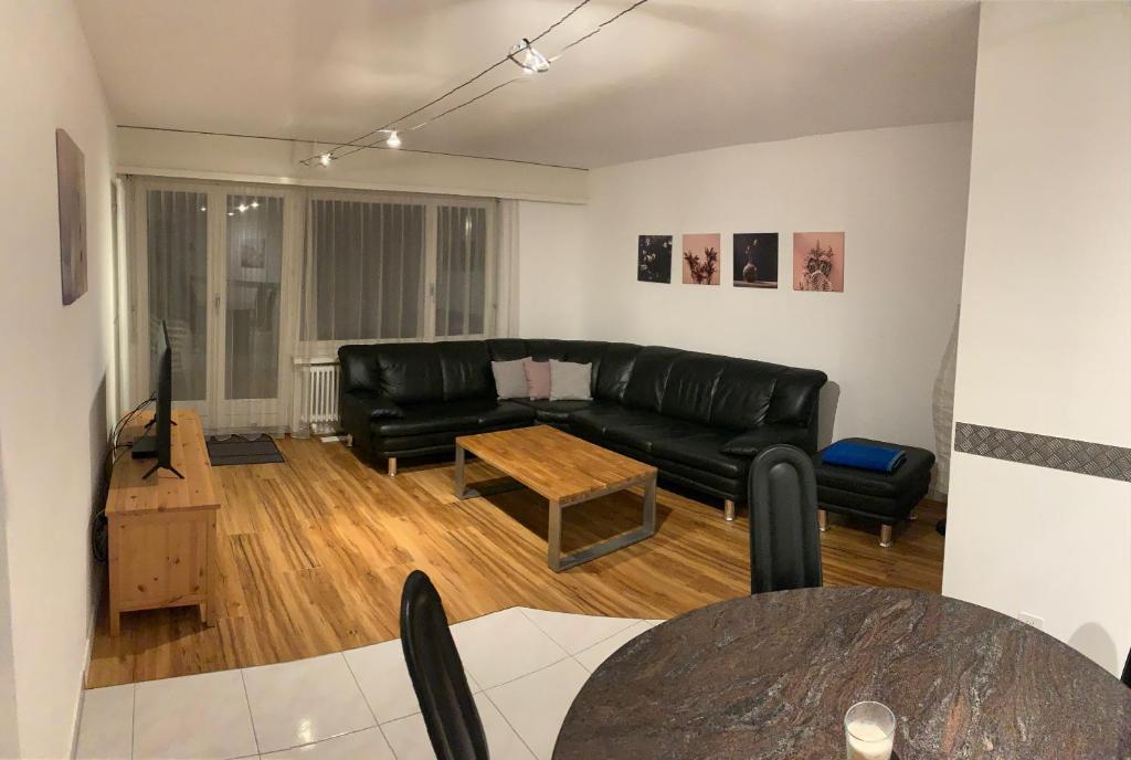 达沃斯Quellenhof C01的客厅配有黑色真皮沙发和桌子