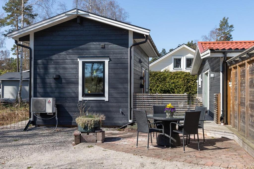 瑟尔沃斯堡Havsstugan的一间黑色的小房子,配有桌子和椅子