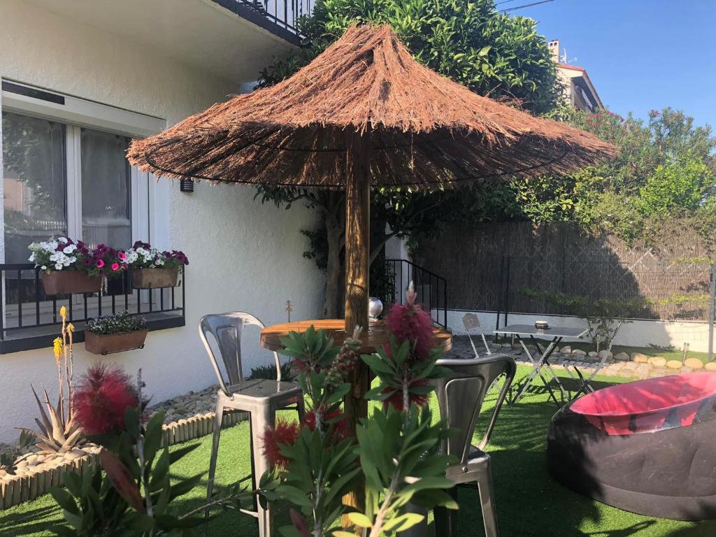 佩皮尼昂Au Bougainvillier的庭院配有桌子、遮阳伞和椅子
