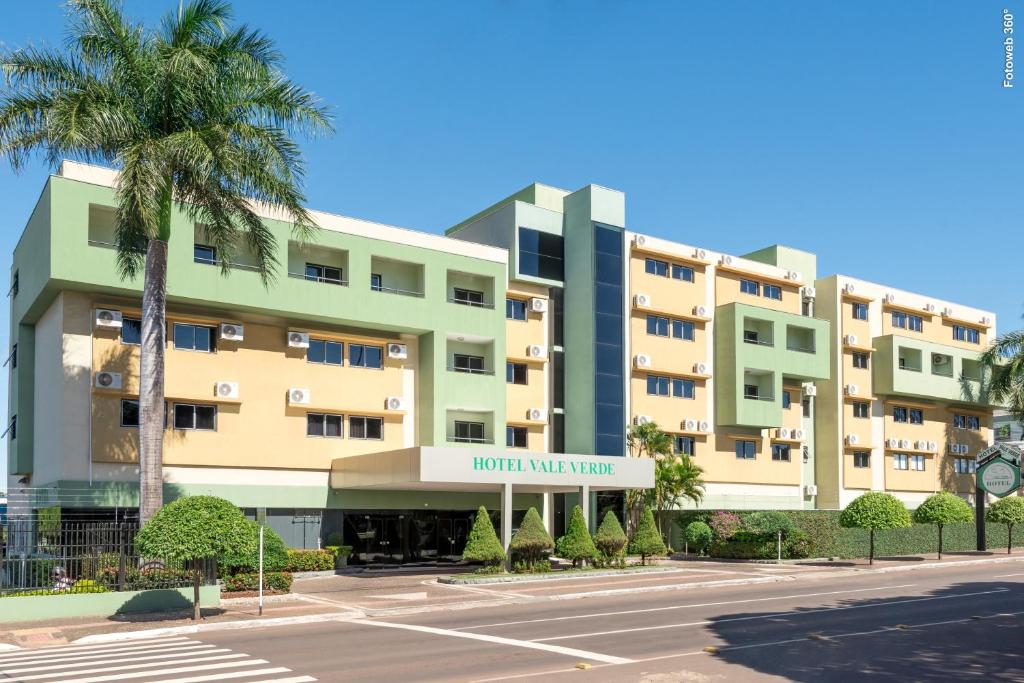 大坎普Hotel Vale Verde的一座棕榈树大型公寓楼和一个停车场