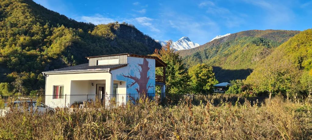 OniRacha Cornfield House的一座白色的小建筑,位于山地