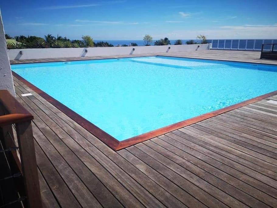 帕皮提Farerei Appartement spacieux, équipé et confortable的木制甲板上的大型蓝色游泳池