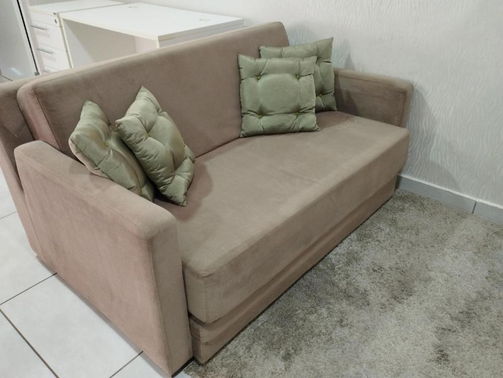 伊瓜苏Ap flat central- ar, garagem e ótima localização的一张带三个枕头的棕色沙发