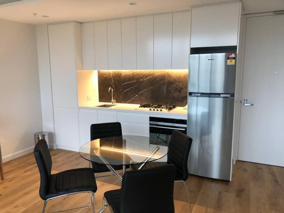 悉尼Beautiful Apartment in Chatswood的厨房配有玻璃桌和不锈钢冰箱