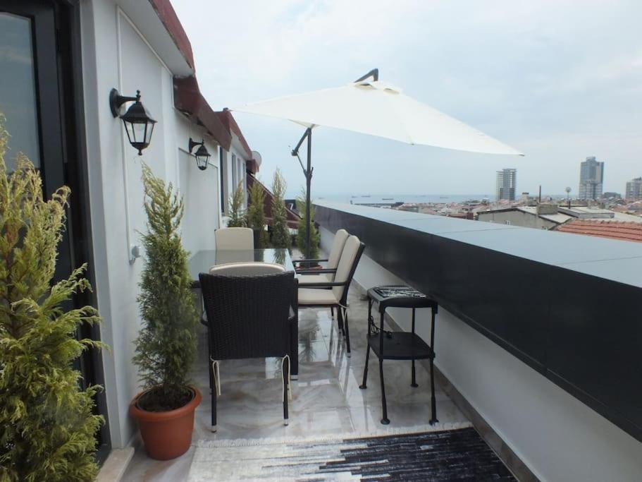 伊斯坦布尔Central Cozy Flat with Terrace & Sea View的阳台配有桌椅和遮阳伞。