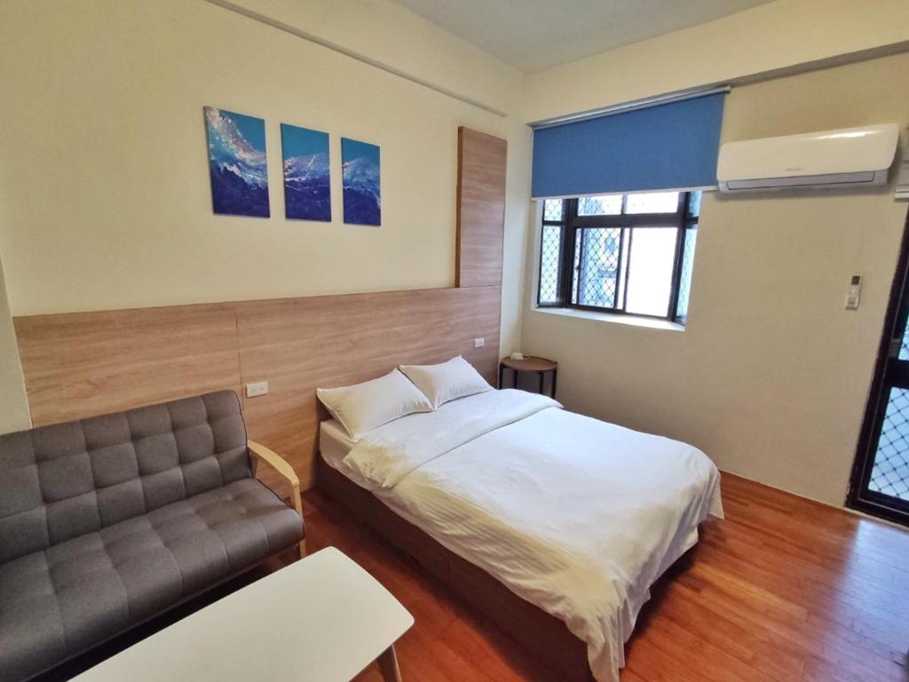 花莲市翼想旅宿-2022營運車站前花蓮民宿的一间卧室配有一张床和一张沙发