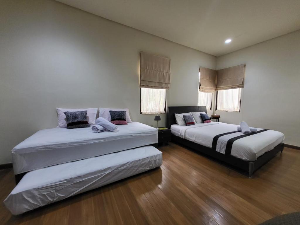 茂物Villa Vimala Hills Semeru的客房内设有两张床,铺有木地板,设有窗户。