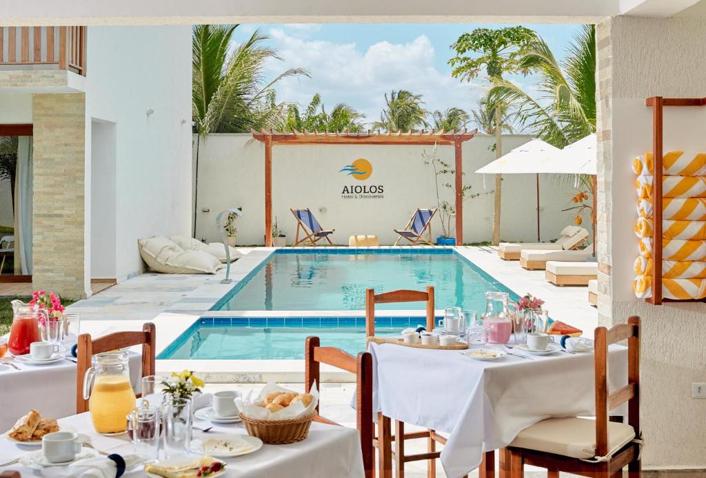 普雷亚Aiolos Hotel & Discoveries的一间带游泳池和桌椅的餐厅