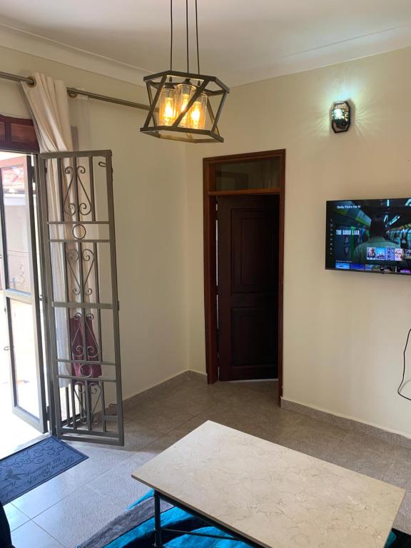 坎帕拉MiniPalais Bukoto的客厅配有桌子和墙上的电视