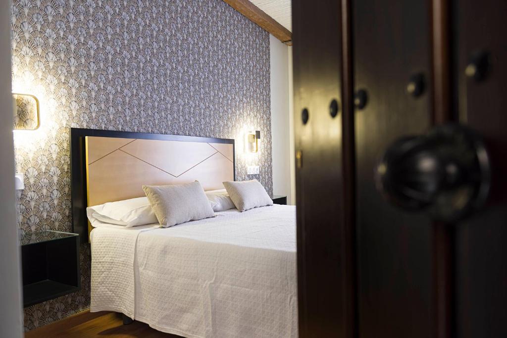 乌贝达Hotel Juancaballo的一间卧室配有带白色床单和枕头的床。