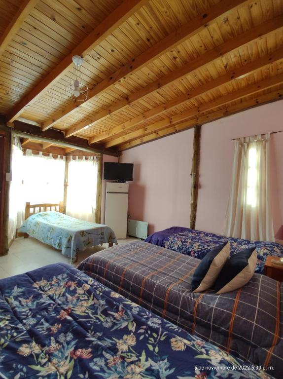 PuelchesHotel Juanita的一间卧室设有两张床和木制天花板