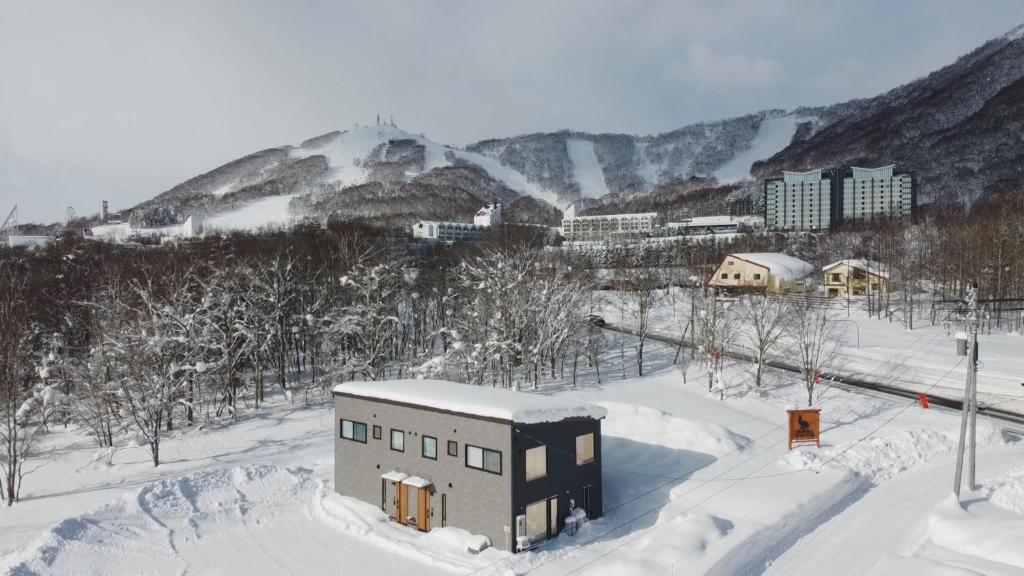 留寿都村WaPura Rusutsu的一座雪地中的建筑,背景是一座山
