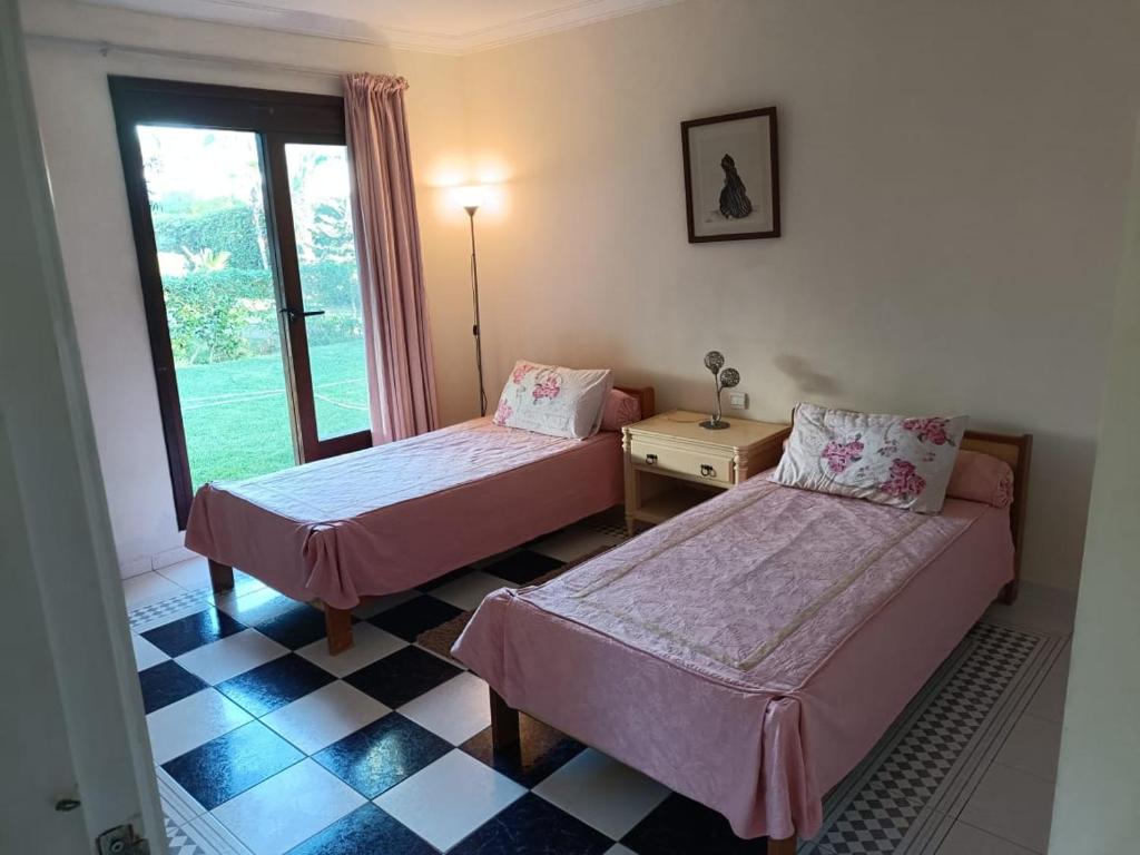 杰迪代Villa meublée face à la mer, Golf et Verdure的客房设有两张床、一张桌子和一扇窗户。