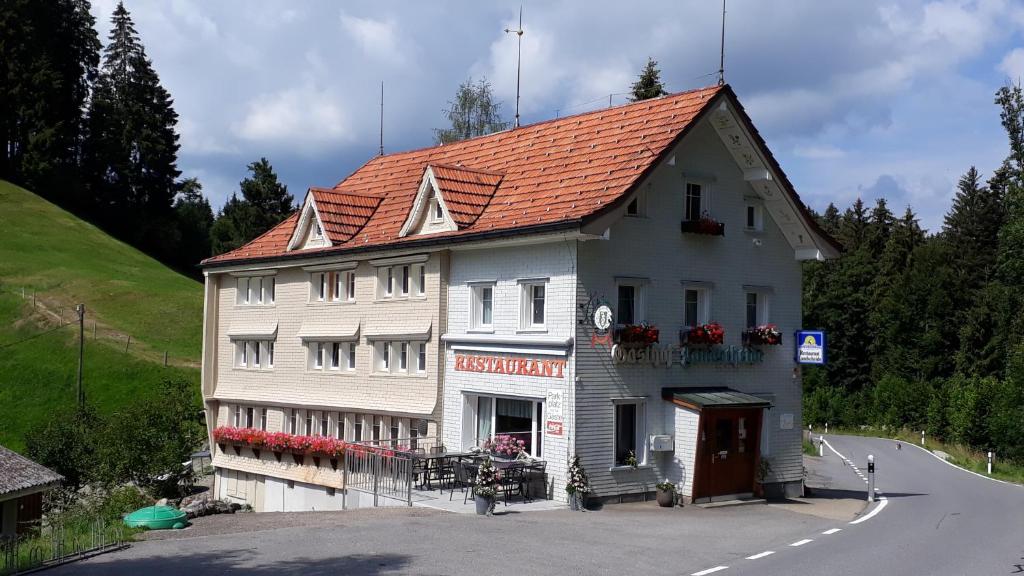 SchwellbrunnSchwellbrunn,Ferienwohnung mit Säntissicht的白色的建筑,在路上有橙色的屋顶