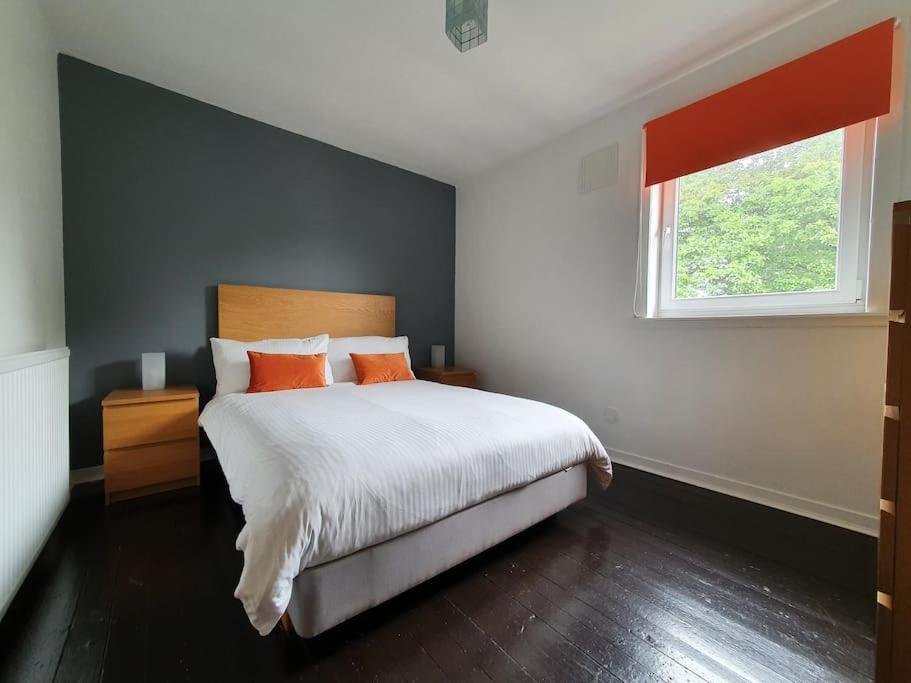 阿伯丁2 Bedroom, free parking & Netflix near hospitals的一间卧室配有带橙色枕头的床和窗户。