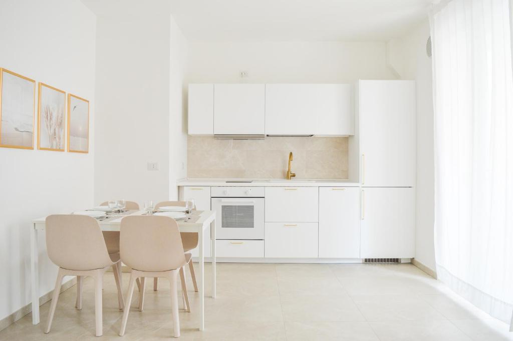 皮内托Homiday - Residenza Caravelle的厨房配有白色橱柜和桌椅