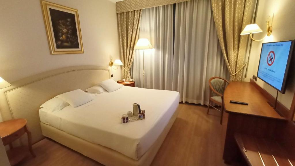 弗利格洛伯斯城贝斯特韦斯特酒店的酒店客房设有一张白色大床和一张书桌