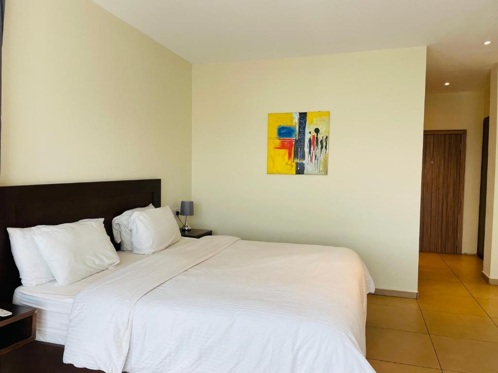 弗里敦新布鲁克菲尔兹酒店的卧室配有白色的床和墙上的绘画作品