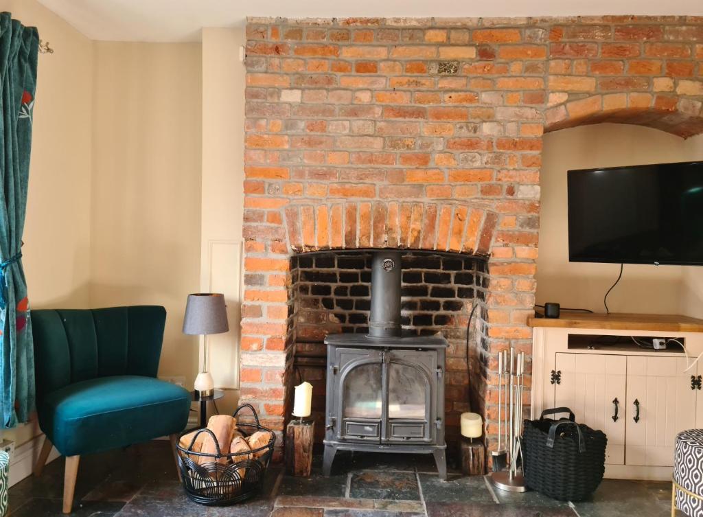 KintburyGorgeous 2 bedroom Kintbury cottage的客厅设有砖砌壁炉和电视。