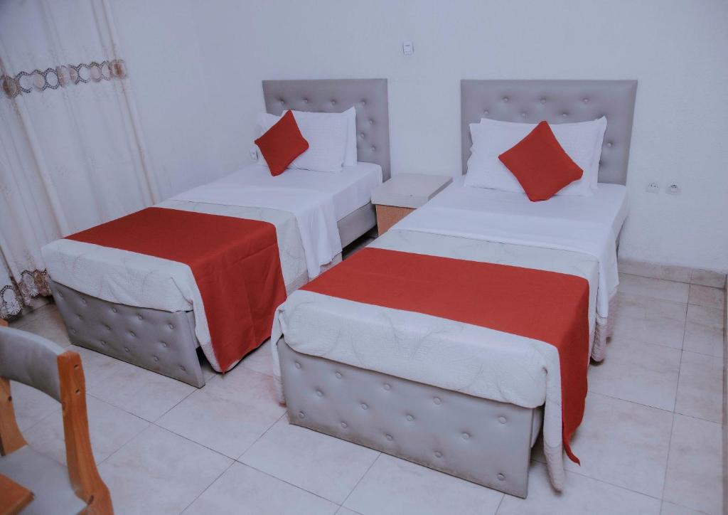 基加利Room in BB - Martin Aviator Hotel的客房配有两张带红白色枕头的床。