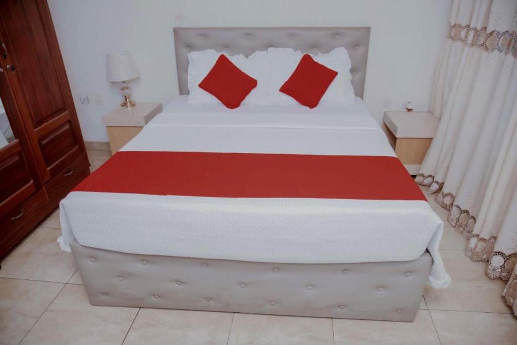 基加利Room in BB - Martin Aviator Hotel的一间卧室配有一张带红色枕头的大床