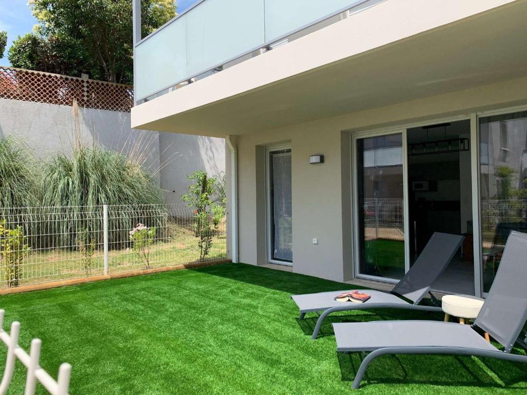 迈兹Appartement Mèze, 3 pièces, 4 personnes - FR-1-604-27的后院设有绿草和两把草坪椅