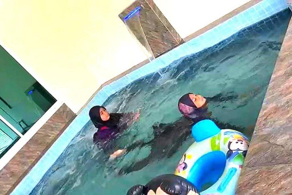 哥打丁宜Desaru 16Pax Family with Private Mini Pool & Jacuzzi的一群人在游泳池游泳