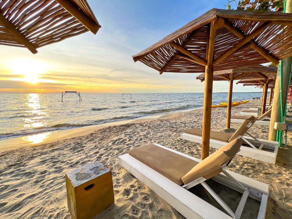 托卢Hotel Camino Verde的日落时在海滩上摆放一组椅子