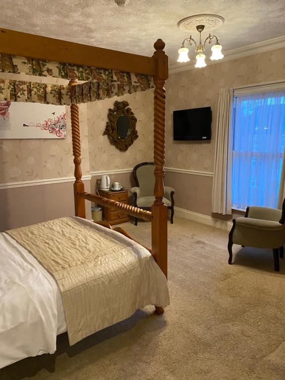 埃文河畔斯特拉特福克罗弗特宾馆的一间卧室配有一张床、一台电视和一把椅子