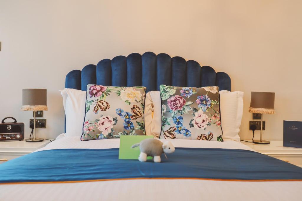 兰卡斯特皇家金斯阿姆酒店的一只泰迪熊坐在一张带有绿色标志的床上