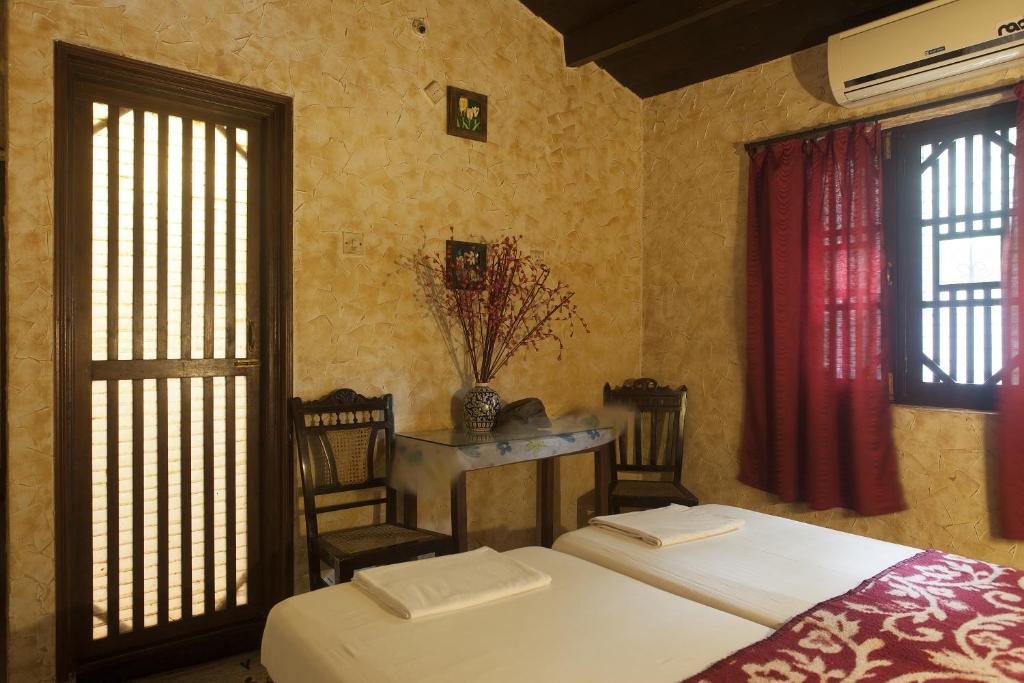 帕纳吉Afonso Guest House的一间卧室设有两张床、一张桌子和窗户。