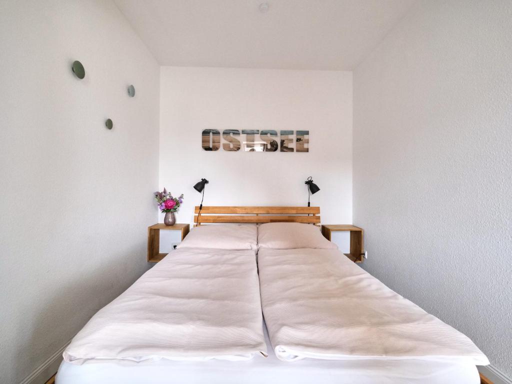 哈里斯莱Ostsee, wunderschöne Wohnung mit Meerblick的白色墙壁间的一张床