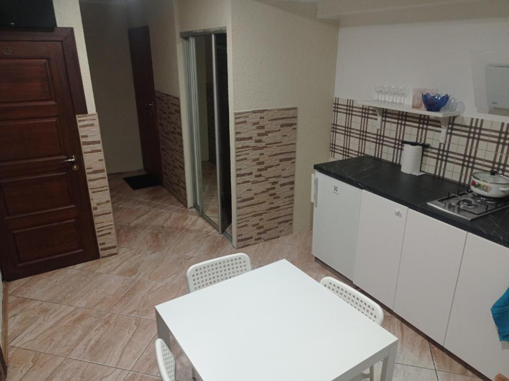 维尔纽斯Apartment parking loft Akaciju的厨房配有白色橱柜和白色的桌椅
