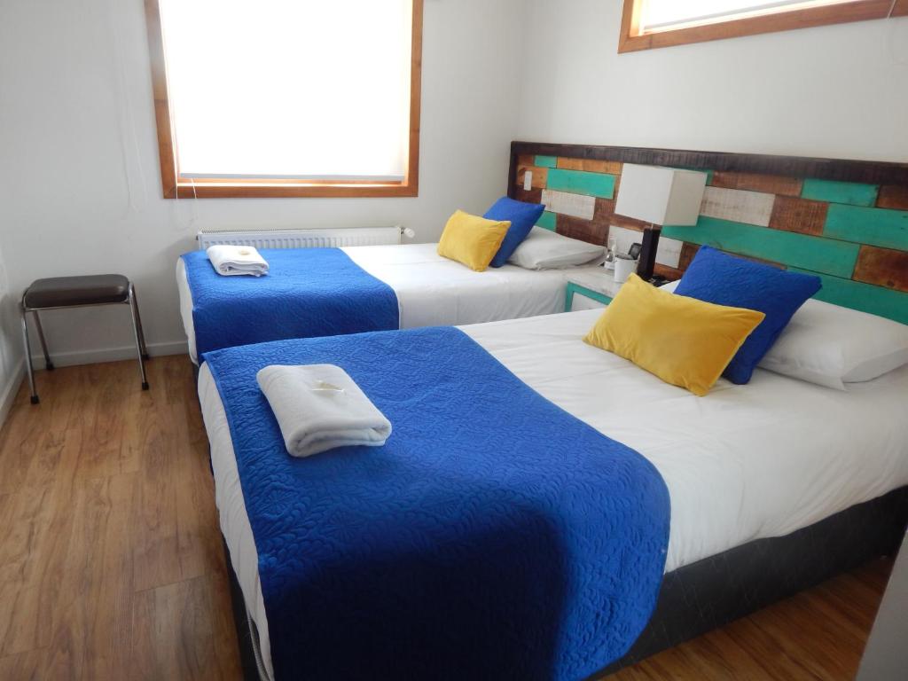 蓬塔阿雷纳斯Hostal Buenavista Patagonia的带3张床和蓝色及黄色枕头的客房
