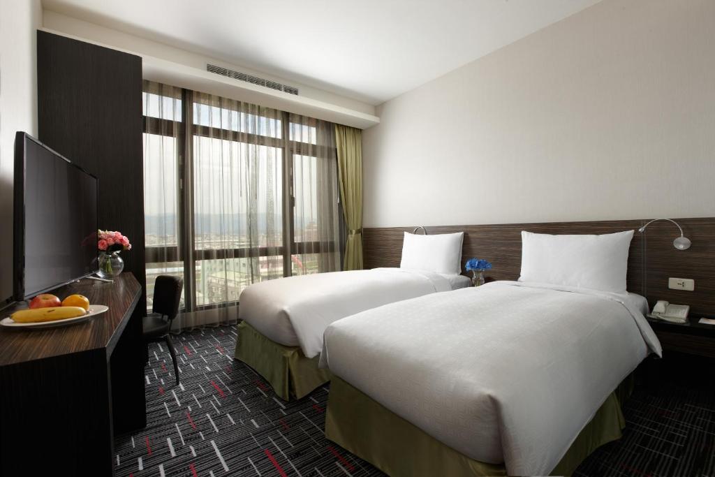 台北首都大饭店松山馆的酒店客房设有两张床和窗户。