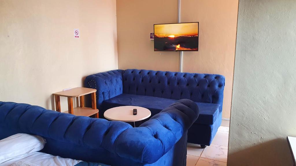 KikuyuLola's Nest along the Highway - Free Parking, Wifi, Netflix & Rooftop views的客厅配有蓝色的沙发和桌子