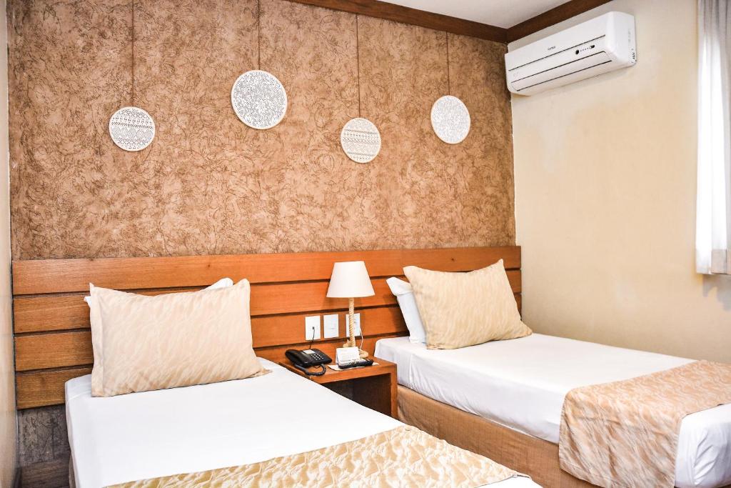 福塔莱萨Carppa Hotel的酒店客房设有两张床和一张桌子。