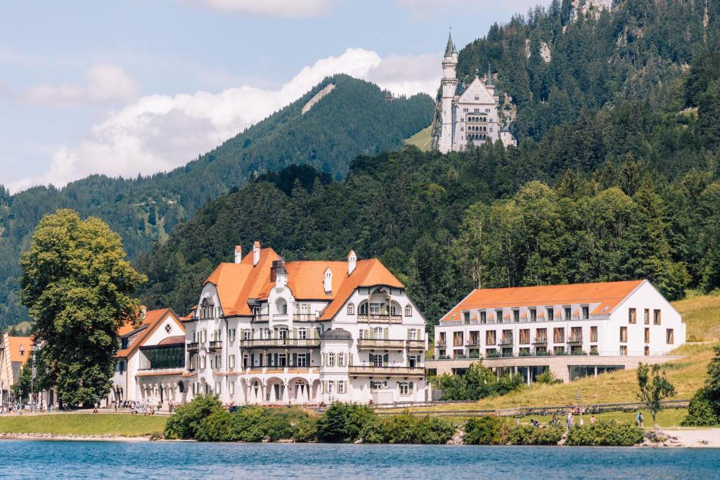 施万高AMERON Neuschwanstein Alpsee Resort & Spa的一座位于湖岸上的大型建筑,拥有一座城堡