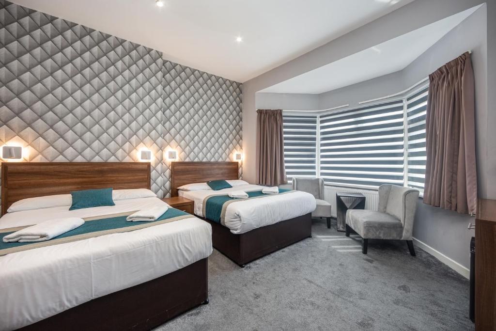 伦敦King Solomon Hotel- Golders Green的酒店客房,配有两张床和椅子