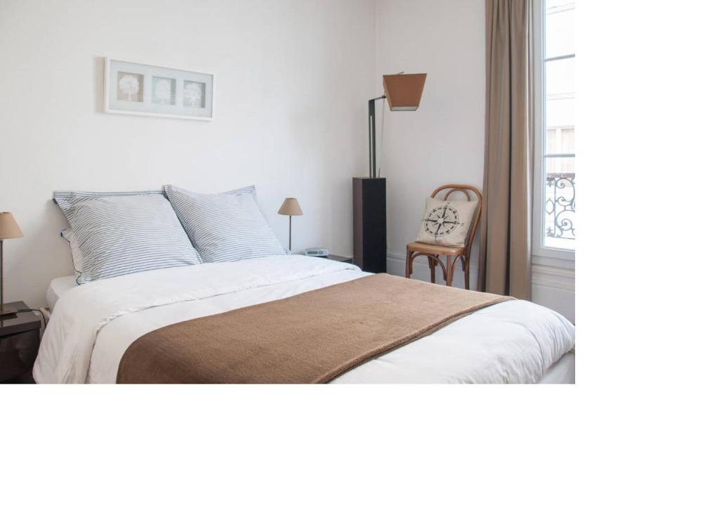 勒瓦卢瓦-佩雷La petite maison parisienne的卧室配有床、椅子和窗户。