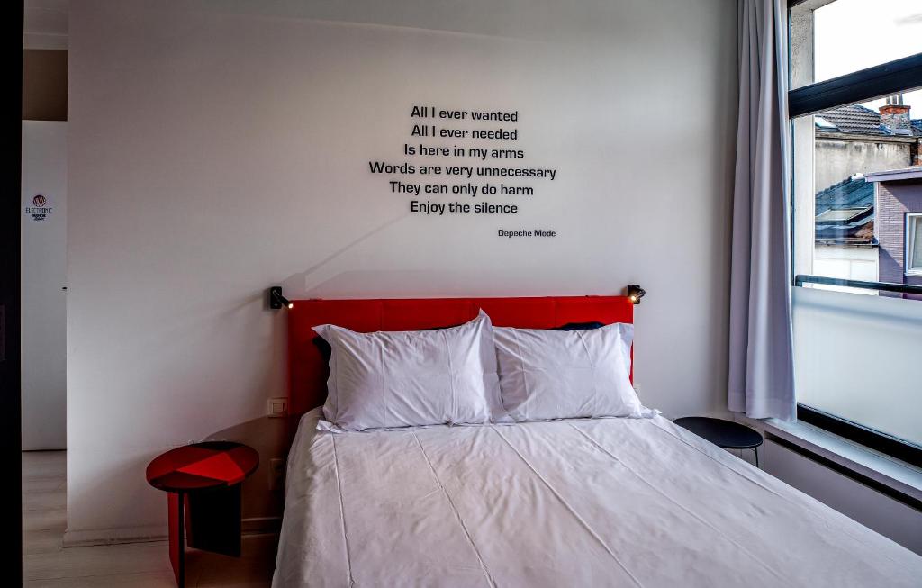 安特卫普摇滚龙虾城住宿加早餐旅馆的一张有红色床头板的床,墙上有句名言