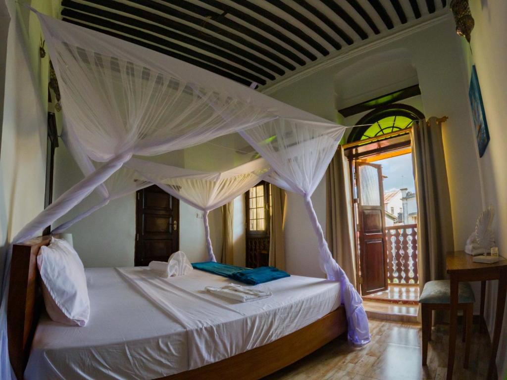 NgamboAurelia Zanzibar的一间卧室配有一张带天蓬的白色床