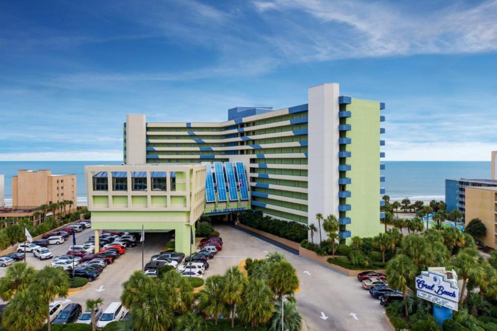 默特尔比奇珊瑚海滩度假酒店的停车场内停放汽车的大型建筑