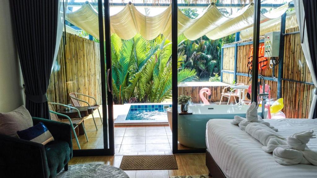 素叻Phetrapoolvilla (เภตราพูลวิลล่า)的一间卧室享有游泳池和浴缸的景致。